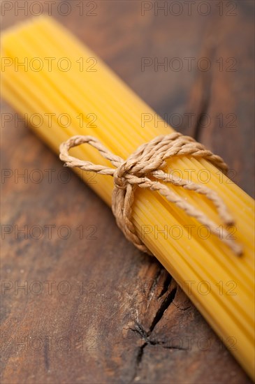 Italian pasta spaghetti tied with a rope on a rustic table