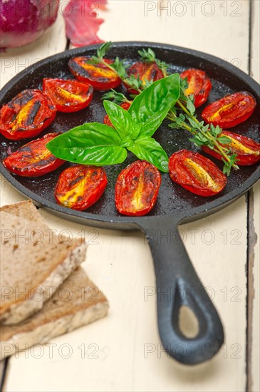 Oven baked cherry tomatoes with basil and thyme on a cast iron skillet