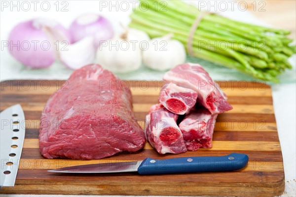 Raw beef and pork ribs with asparagus and herbs ready to cook