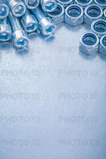 Copy space image of threaded stainless bolts and nuts on metallic background construction concept