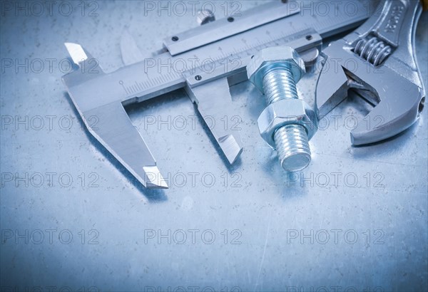 Metal brake caliper adjustable spanner bolt and nut on scratched metallic background construction concept