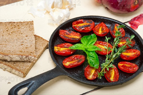 Oven baked cherry tomatoes with basil and thyme on a cast iron skillet