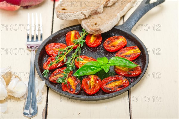 Oven baked cherry tomatoes with basil and thyme on a cast iron skillet