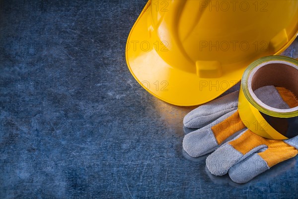 Safety tape hard hat and protective gloves on scratched metallic background copy space image construction concept