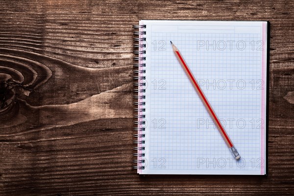 Pencil and clean square copybook on pine brown wooden board office concept