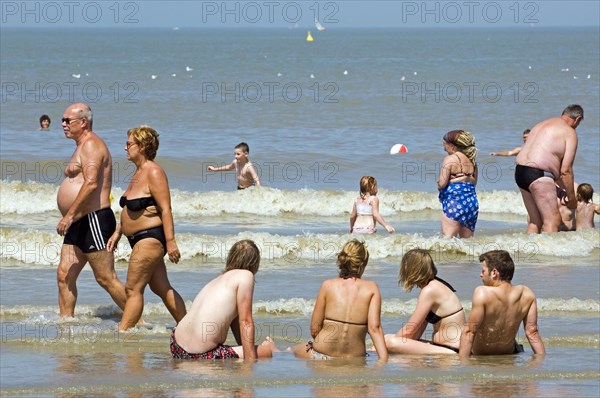 Tourists in swimsuits paddling and swimming in water during the summer holidays along the North Sea coast