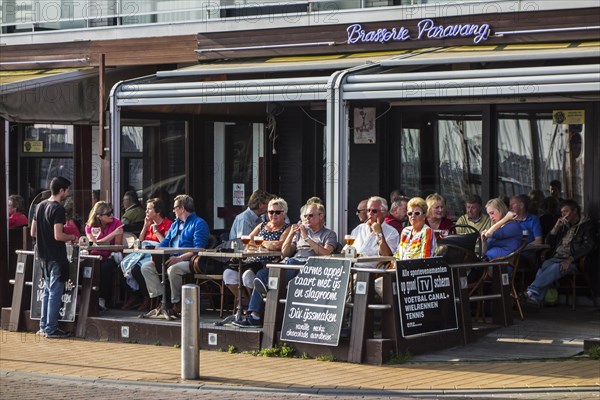 Tourists sitting in a pavement cafe with a beer in seaside resort Blankenberge along the Belgian North Sea coast