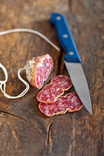 Slicing italian salame pressato pressed over old wood table