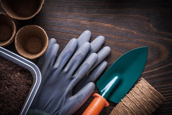 Hand shovel rubber gloves gardening box with soil and peat jars on vintage wooden background agriculture concept