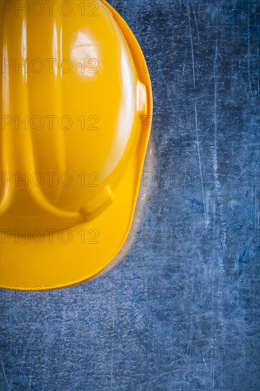 Hard hat on scratched vintage metallic background construction concept