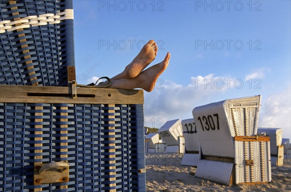Feet sticking out from roofed wicker beach chair at Sylt