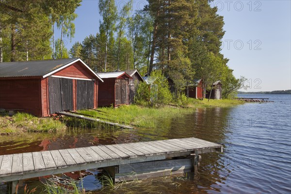 Red wooden boathouses along lake Siljan in summer