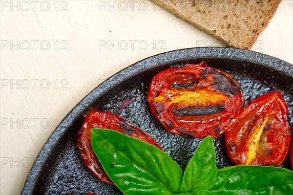 Oven baked cherry tomatoes with basil and thyme on a cast iron skillet