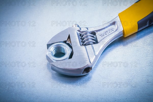 Adjustable spanner and nut on metallic background Design concept