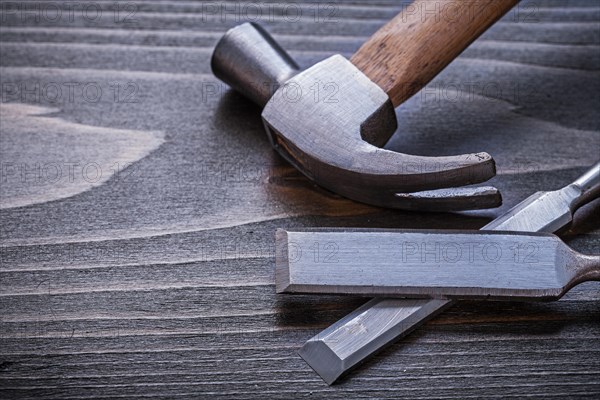 Claw hammer and flat chisel on vintage wooden panel Construction concept