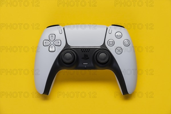 Controller of the PS5 Playstation game console from Sony in front of a monochrome yellow background