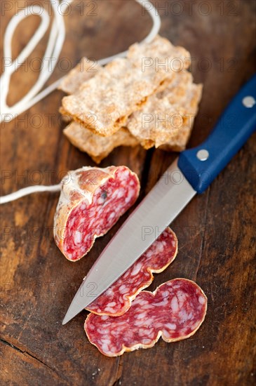 Slicing italian salame pressato pressed over old wood table