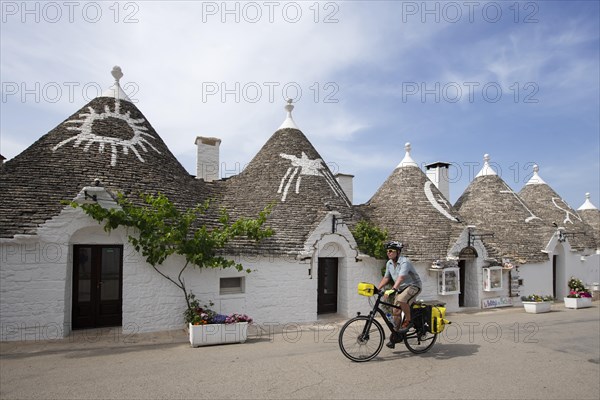 Cyclist between trulli in Alberobello