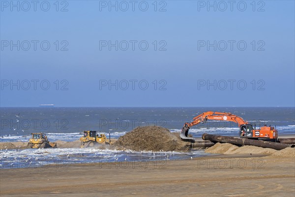 Bulldozers and hydraulic excavator installing pipeline during sand replenishment