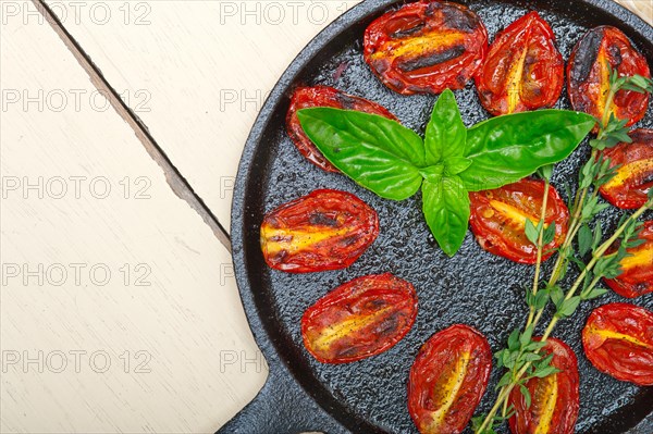 Oven baked cherry tomatoes with basil and thyme on a cast iron skillet