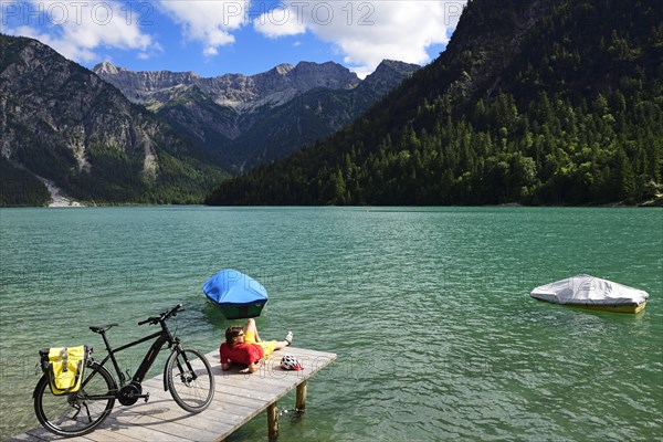 Cyclist taking a break on a wooden footbridge at Plansee