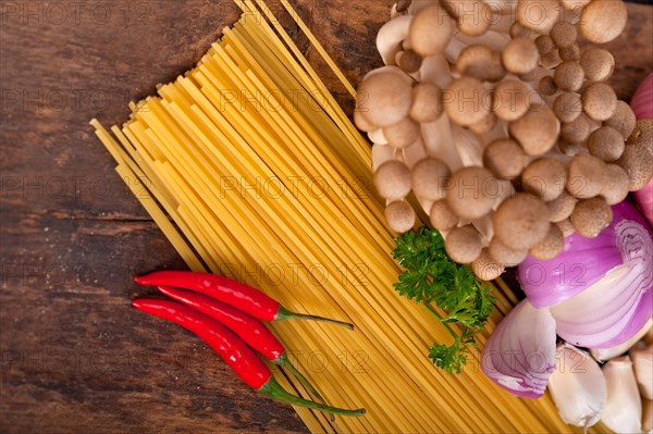 Italian pasta and mushroom sauce raw ingredients over rustic old wood