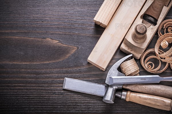 Planner claw hammer metal chisel wooden bolt and curled shavings on vintage wooden board building concept