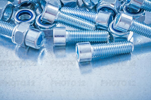 Composition of metal nuts and bolts on a flat metallic background Design concept