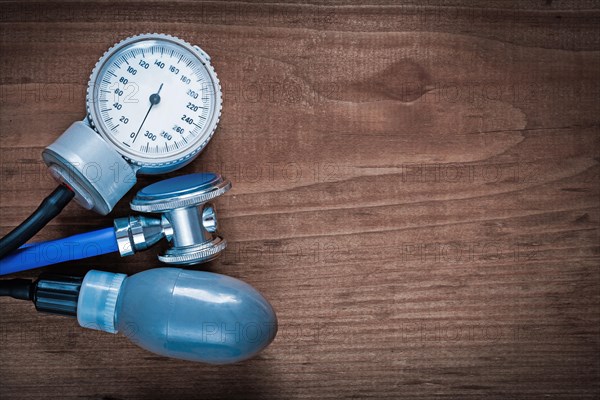 Medical stethoscope and blood pressure monitor on vintage wooden pine board medicine concept