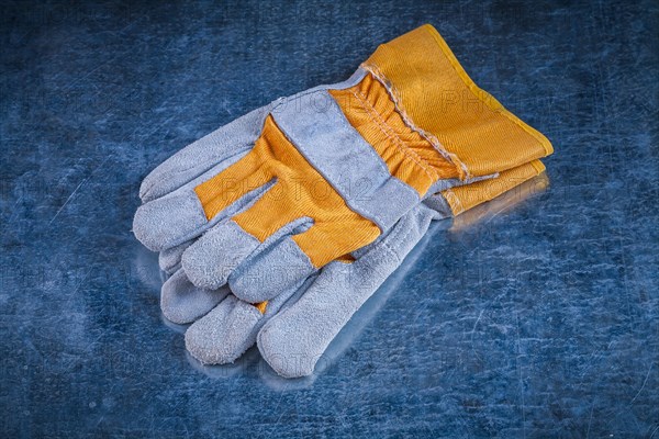 Pair of safety work gloves on scratched vintage metallic background close up image construction concept