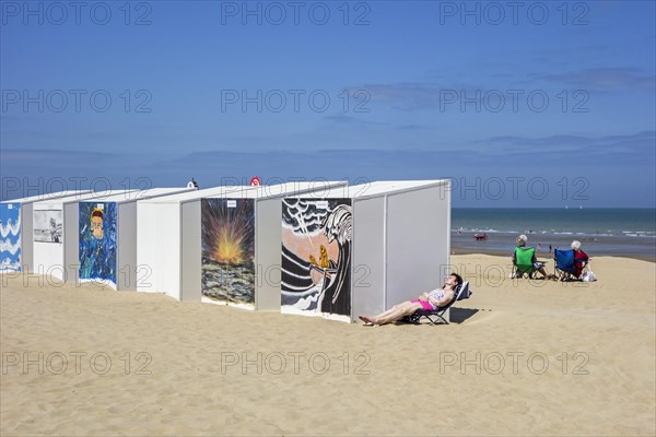 Decorated beach cabins and elderly women sunning on the beach along the North Sea coast