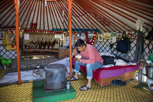 Mongol man eating inside traditional Mongolian ger
