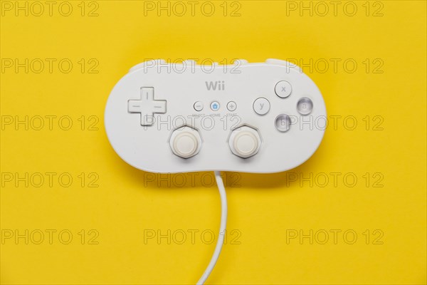 Classic game controller Nintendo Wii game console in front of plain yellow background