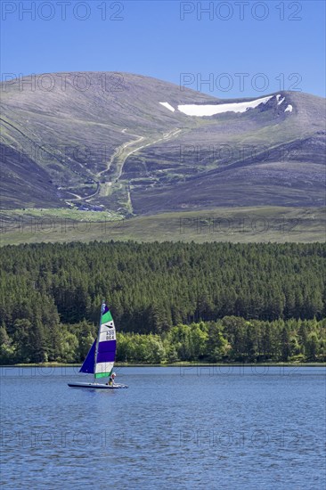 Sailing boat on Loch Morlich in front of the Cairngorm Mountains