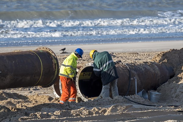 Dredging workers connecting pipes of pipeline during sand replenishment