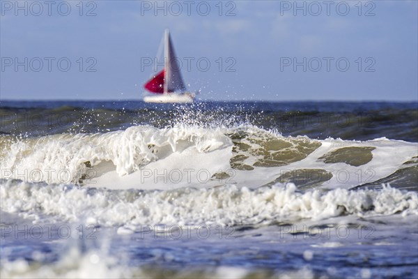 Wave breaking on the beach and sailing boat