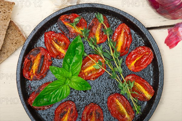 Oven baked cherry tomatoes with basil and thyme on a cast iron skillet