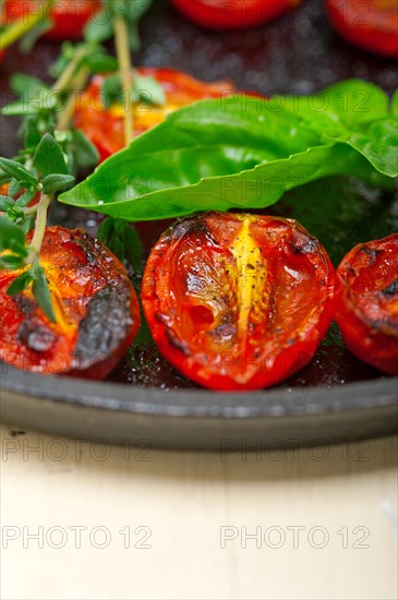 Oven baked cherry tomatoes with basil and thyme on a cast iron skillet