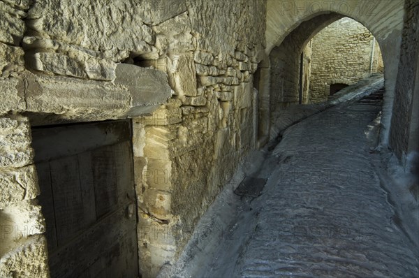 Old wooden door in alley of the medieval village Gordes