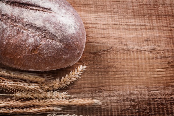 Bundle of wheat ears long loaf on oak wooden board Food and drink concept