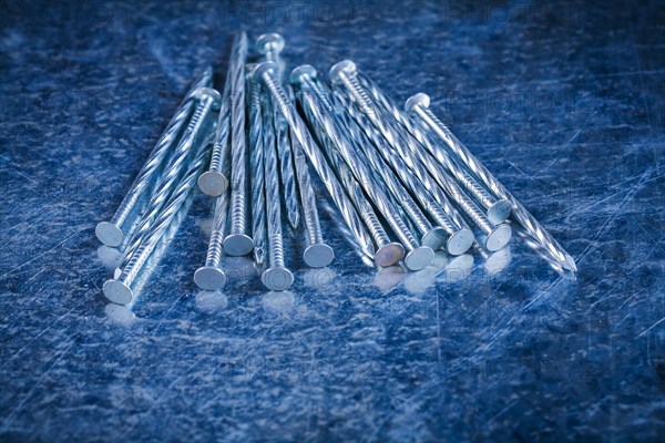 Pile of stainless steel nails on scratched metallic background Maintenance concept