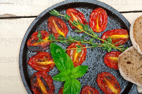 Oven baked cherry tomatoes with basil and thyme on a cast iron skillet