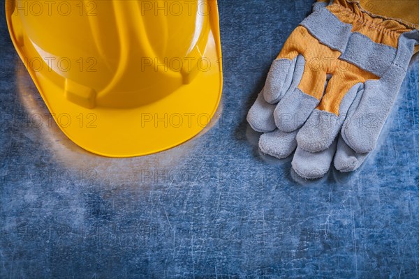 Construction helmet and protective work gloves on scratched metal surface Construction concept