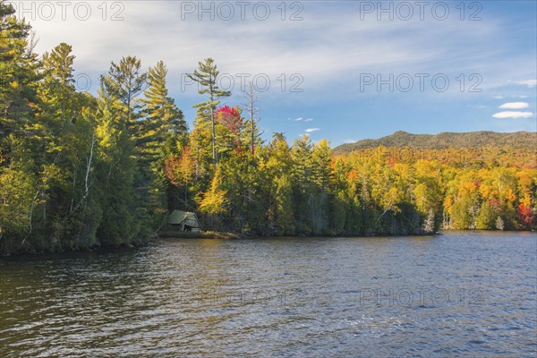 Trees showing autumn colours and old boathouse along Elk Lake in the Adirondack Park