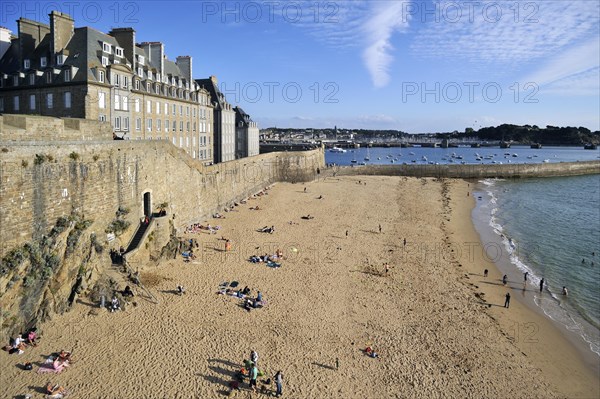 Tourists sunbathing on beach in front of rampart at Saint-Malo