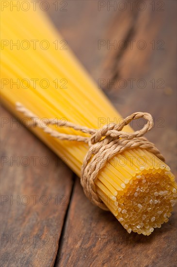 Italian pasta spaghetti tied with a rope on a rustic table