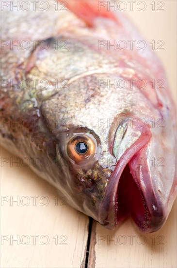 Fresh whole raw fish on a wooden table ready to cook