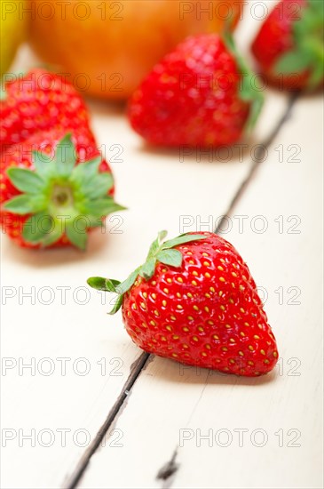 Fresh fruits apples pears and strawberry on a white wood table