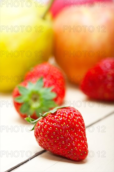 Fresh fruits apples pears and strawberry on a white wood table