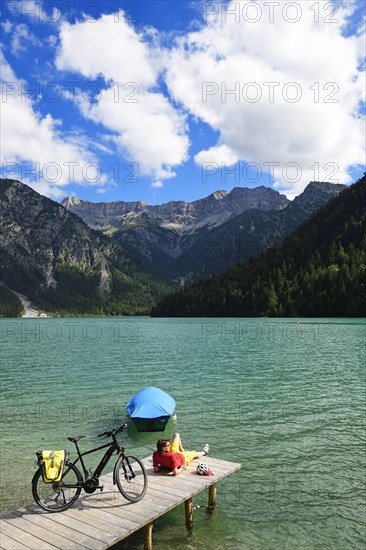 Cyclist taking a break on a wooden footbridge at Plansee